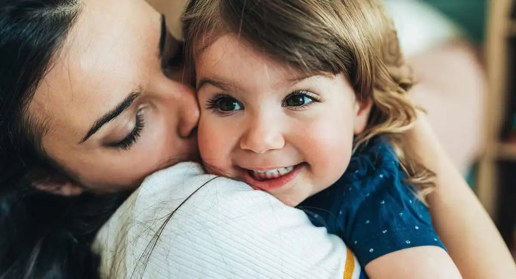 Madre besando a un niño pequeño feliz
